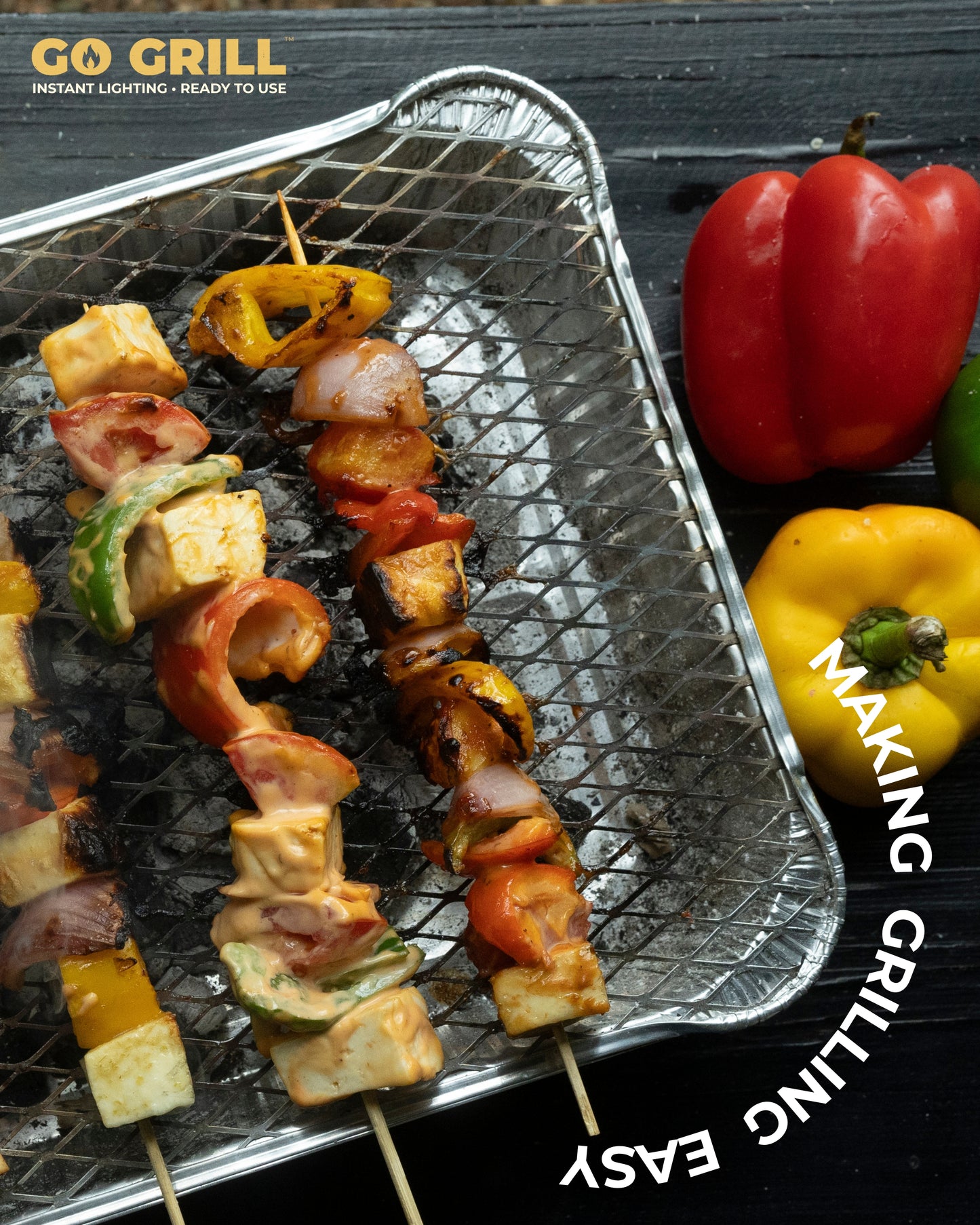 Go Grill disposable BBQ grill with sizzling vegetable and paneer skewers, placed next to colorful bell peppers – perfect for easy outdoor grilling.